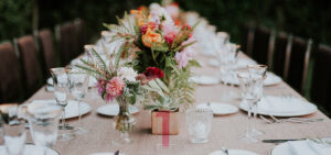 A long table set with white plates and place settings for a formal dinner event.