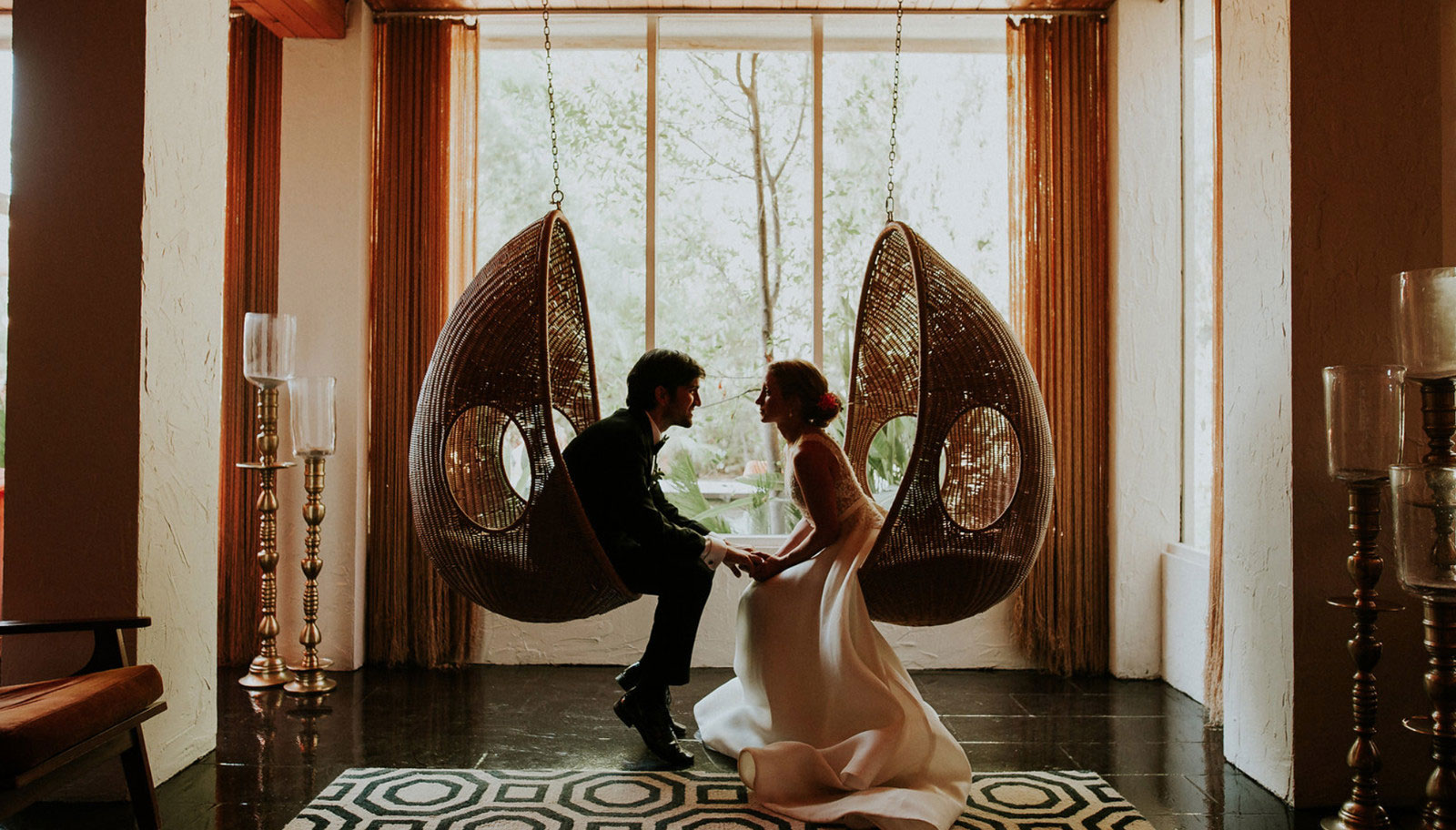 A bride and groom happily sit in a suspended chair, capturing a moment of joy and love on their special day.